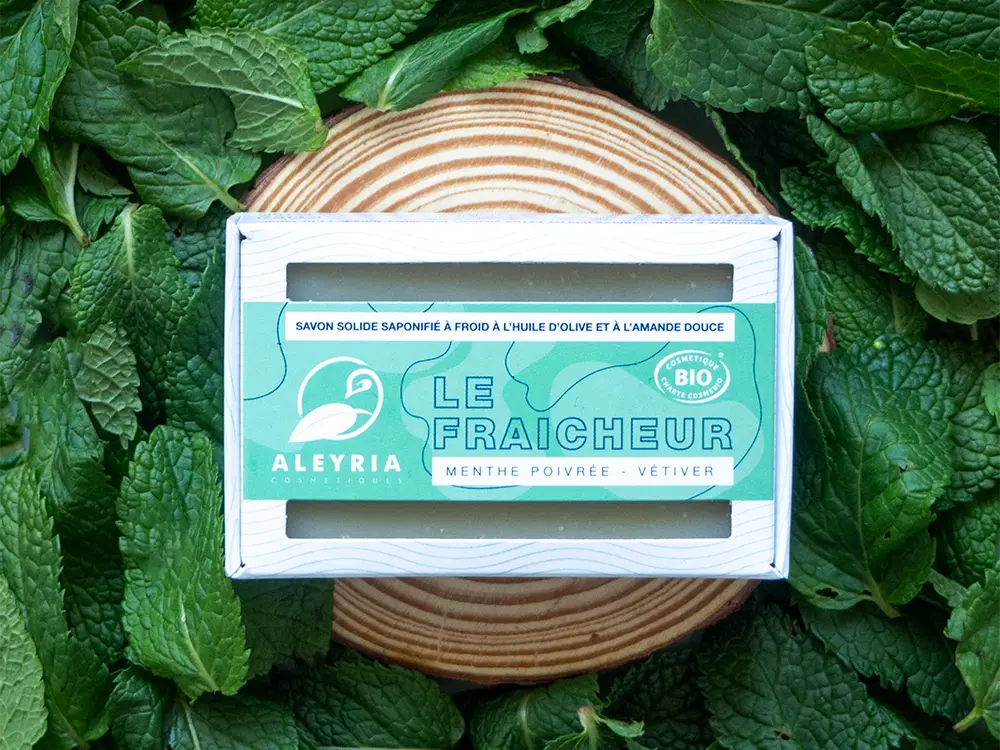 Un savon solide LE Fraicheur posé sur des feuilles de menthe.