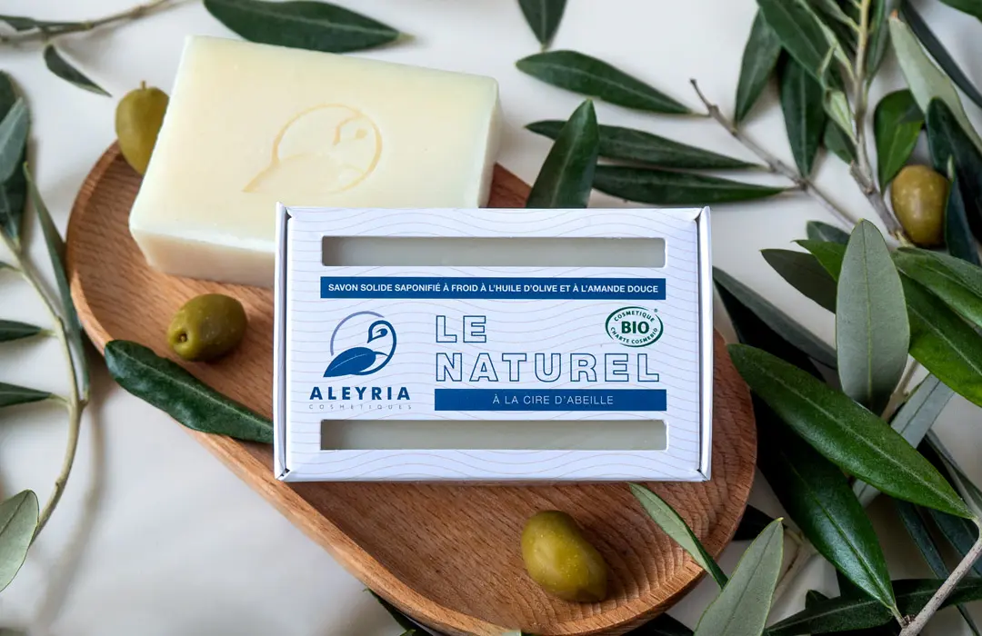 Un boite de savon solide Le Naturel, posé sur une coupole en bois et entouré de branches d'olivier