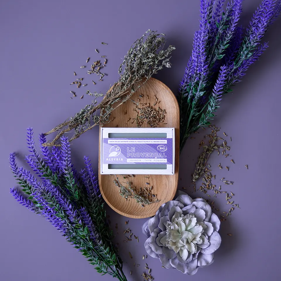 Une boite de savon solide Le Provençal posé sur une coupelle en bois entouré de lavande, de thym et de romarin