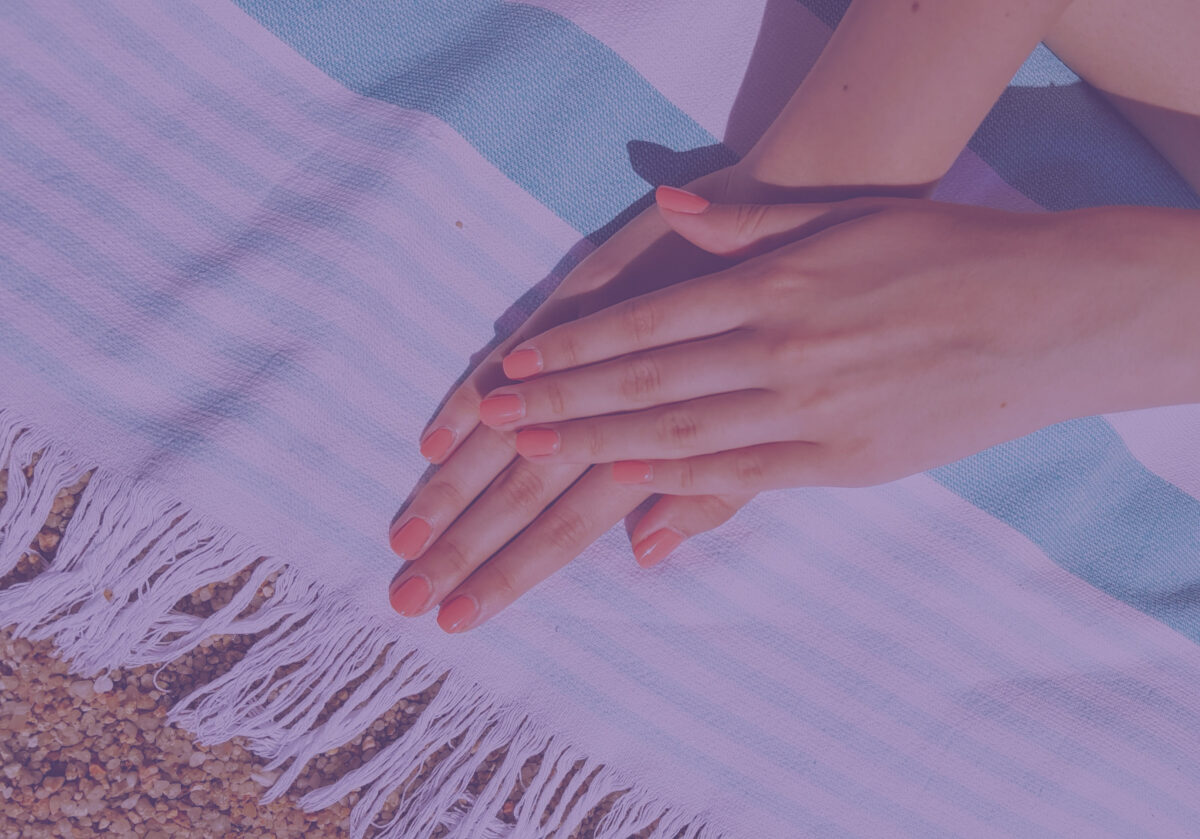 Deux mains au soleil, sur une serviette de plage