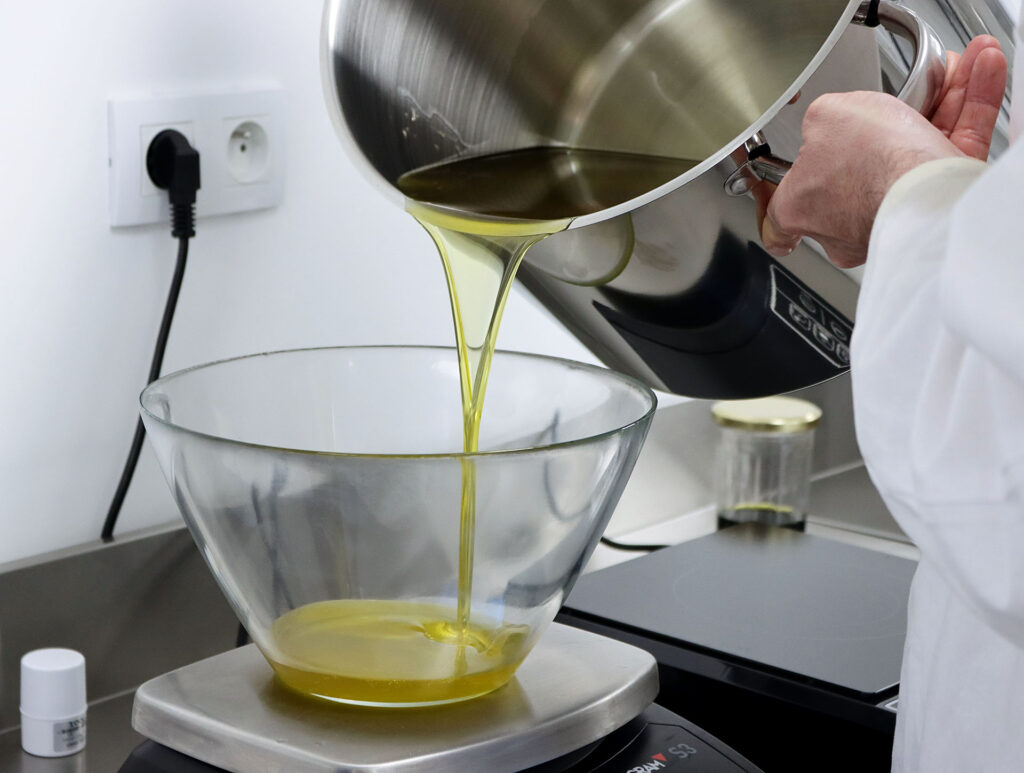 Notre artisan savonnier entrain de verser une huile d'olive extra vierge dans un récipient