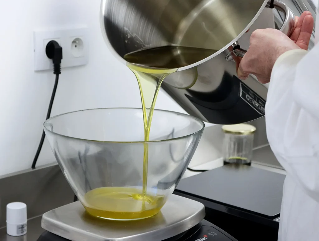 Notre artisan savonnier entrain de verser une huile d'olive extra vierge dans un récipient