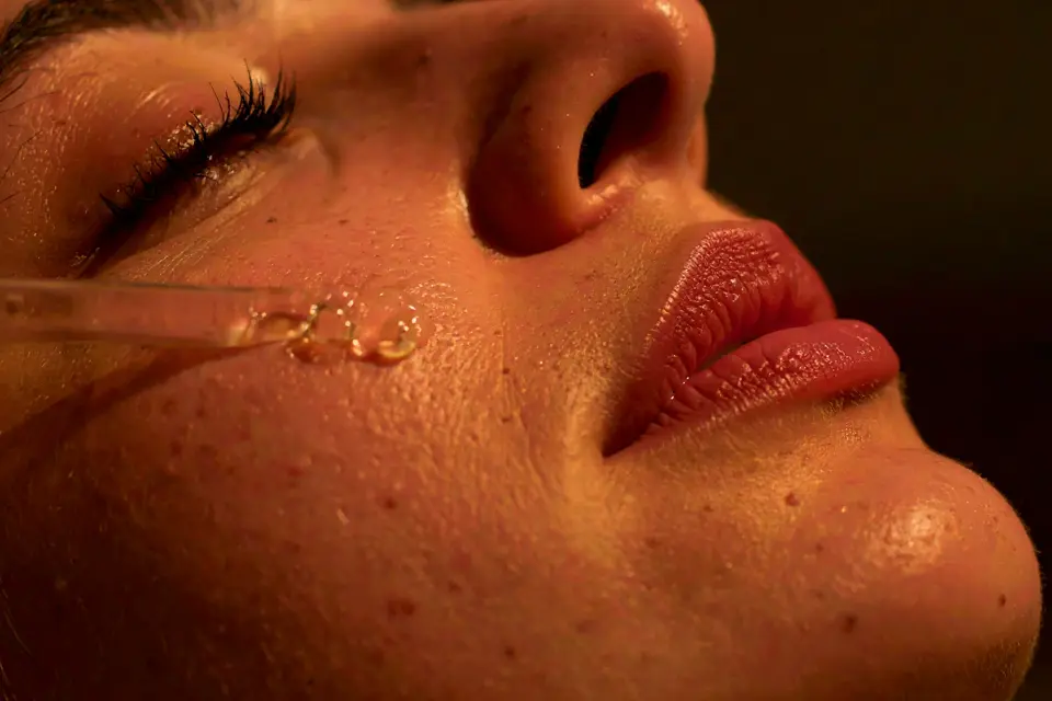 Un visage féminin avec une pipette qui applique du sérum régulateur