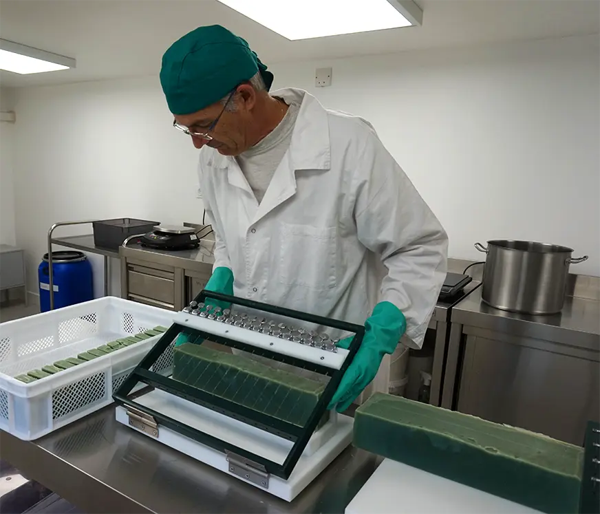 Un savonnier entrain de découper des savons solides dans notre laboratoire à Velaux